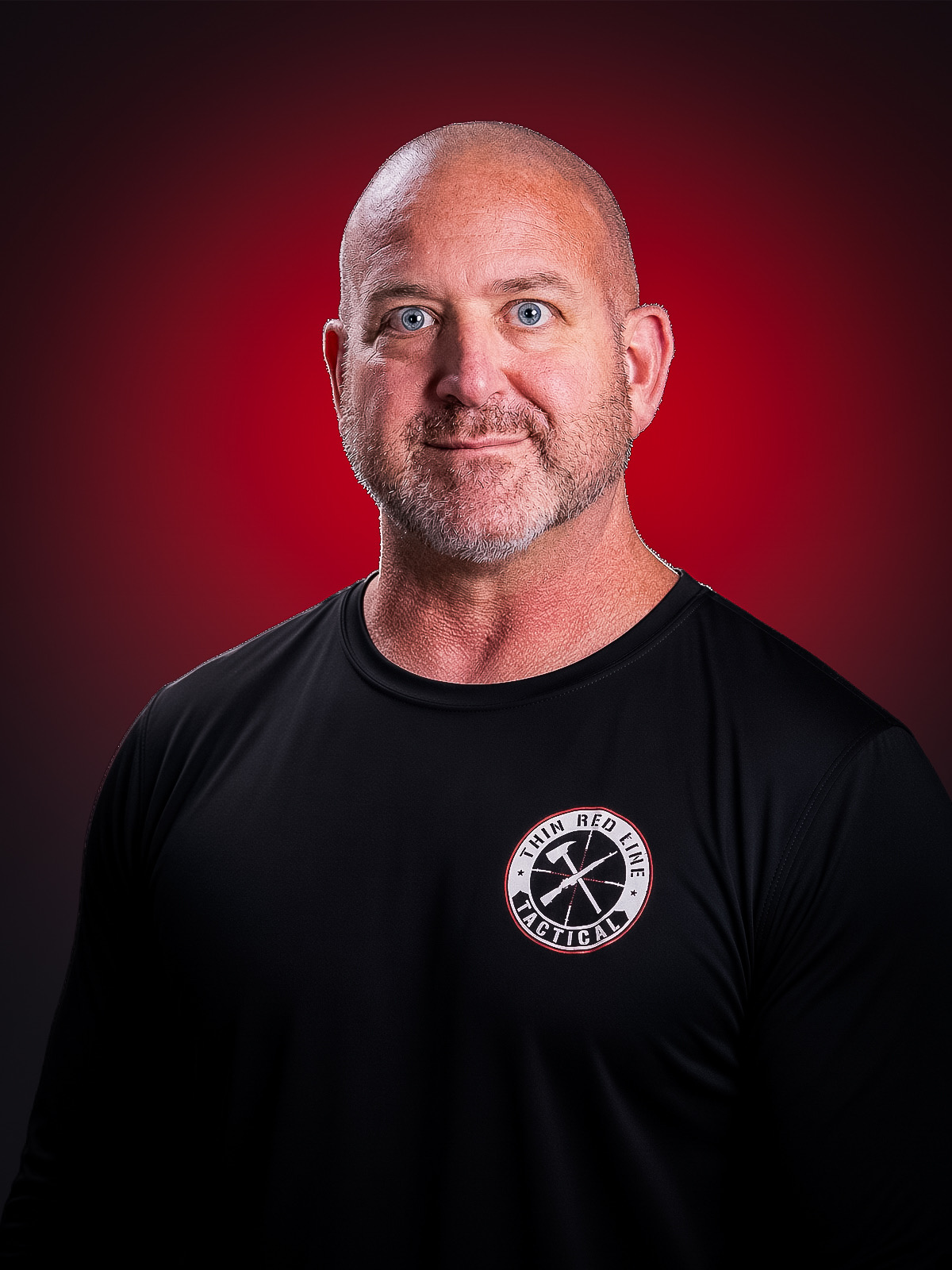 Thin Red Line Tactical founder wearing a black TRLT shirt against a red studio background